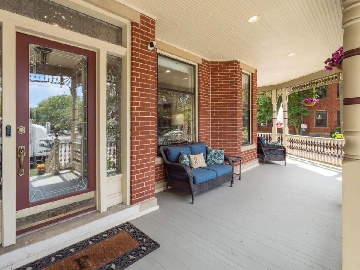 A classic covered porch with a spacious seating area, featuring wicker furniture and vibrant cushions.