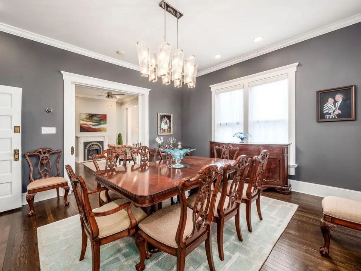 This dining room exudes timeless elegance, featuring a rich mahogany dining set with intricately carved chairs and a matching buffet.