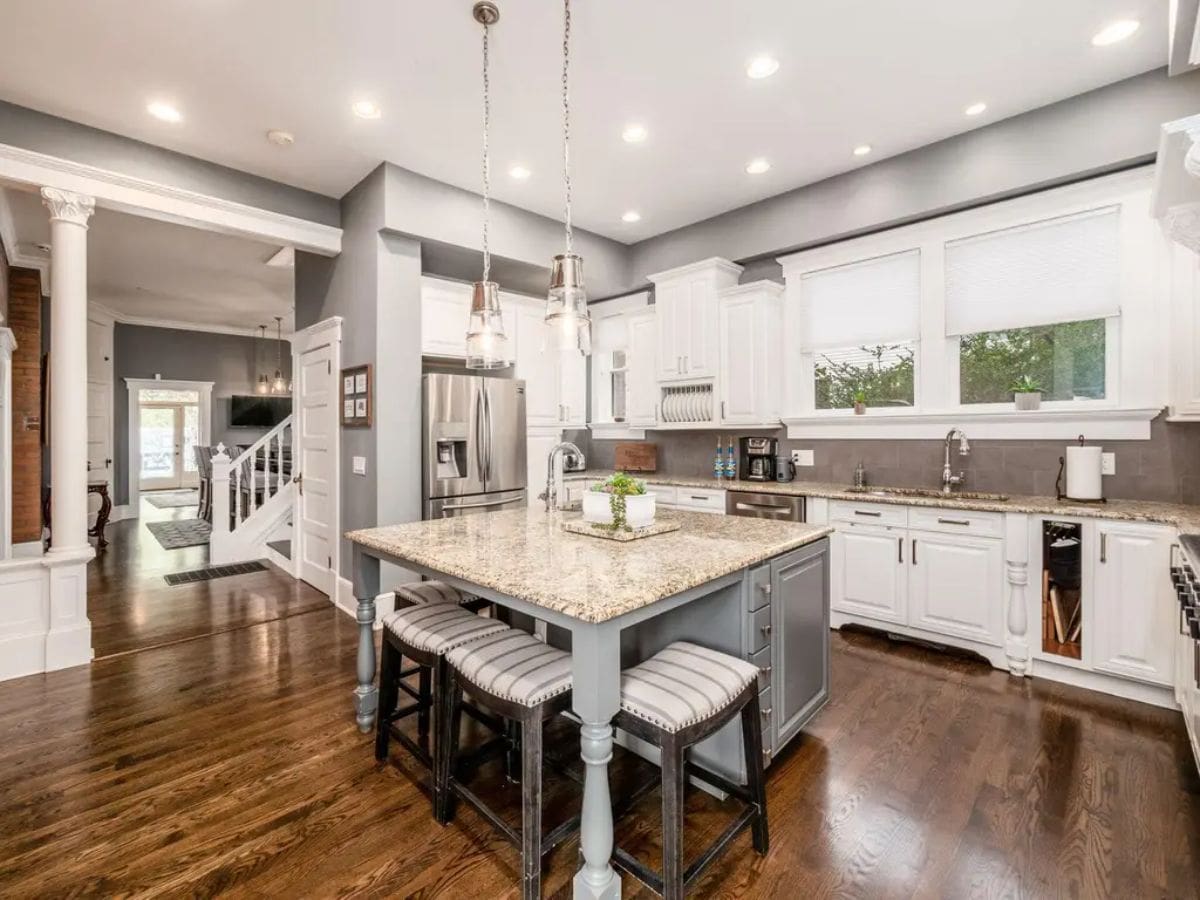 Kitchen combines modern functionality with timeless design, featuring white cabinetry, granite countertops, and stainless steel appliances.
