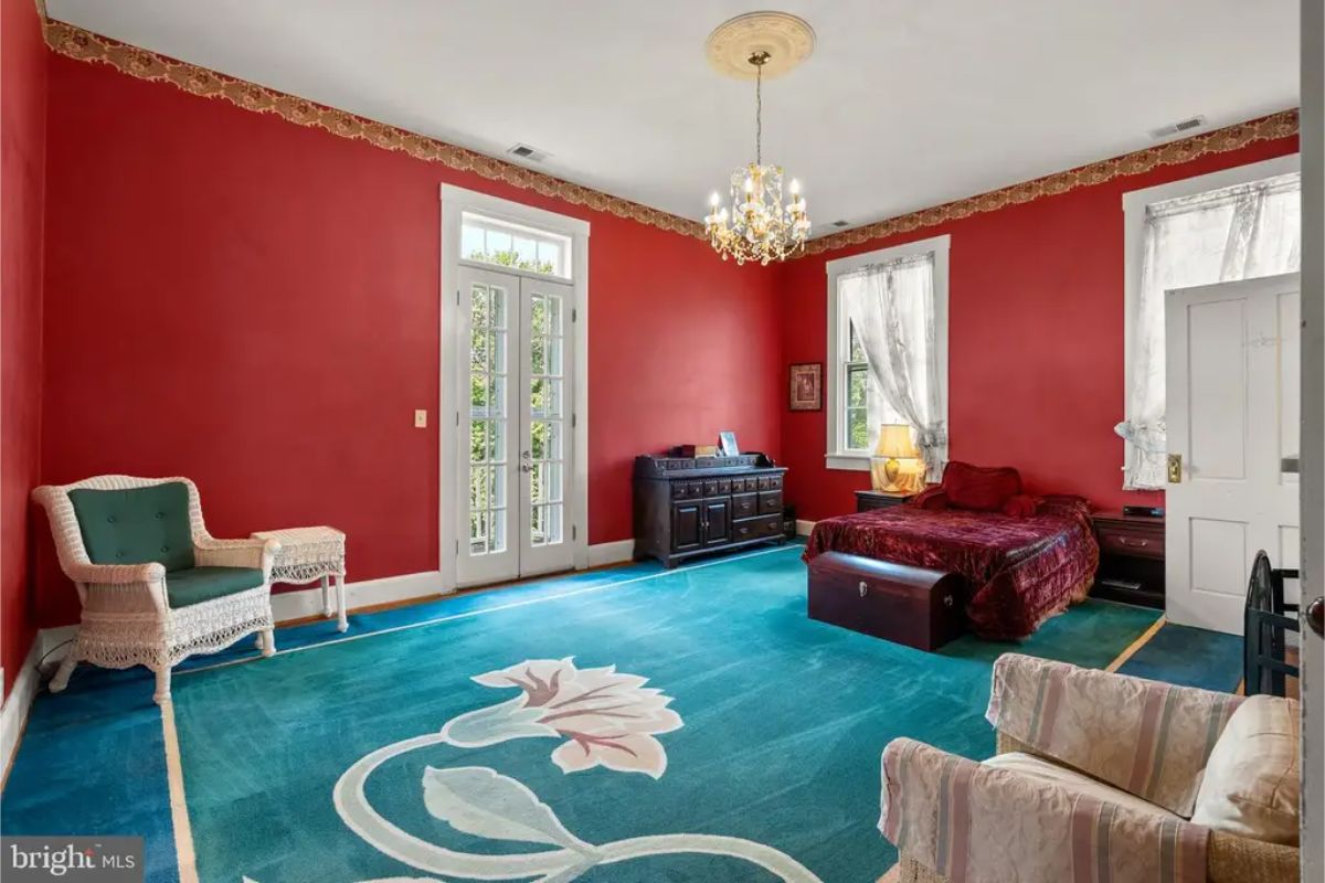 Large bedroom features bold red walls paired with white trim and windows.