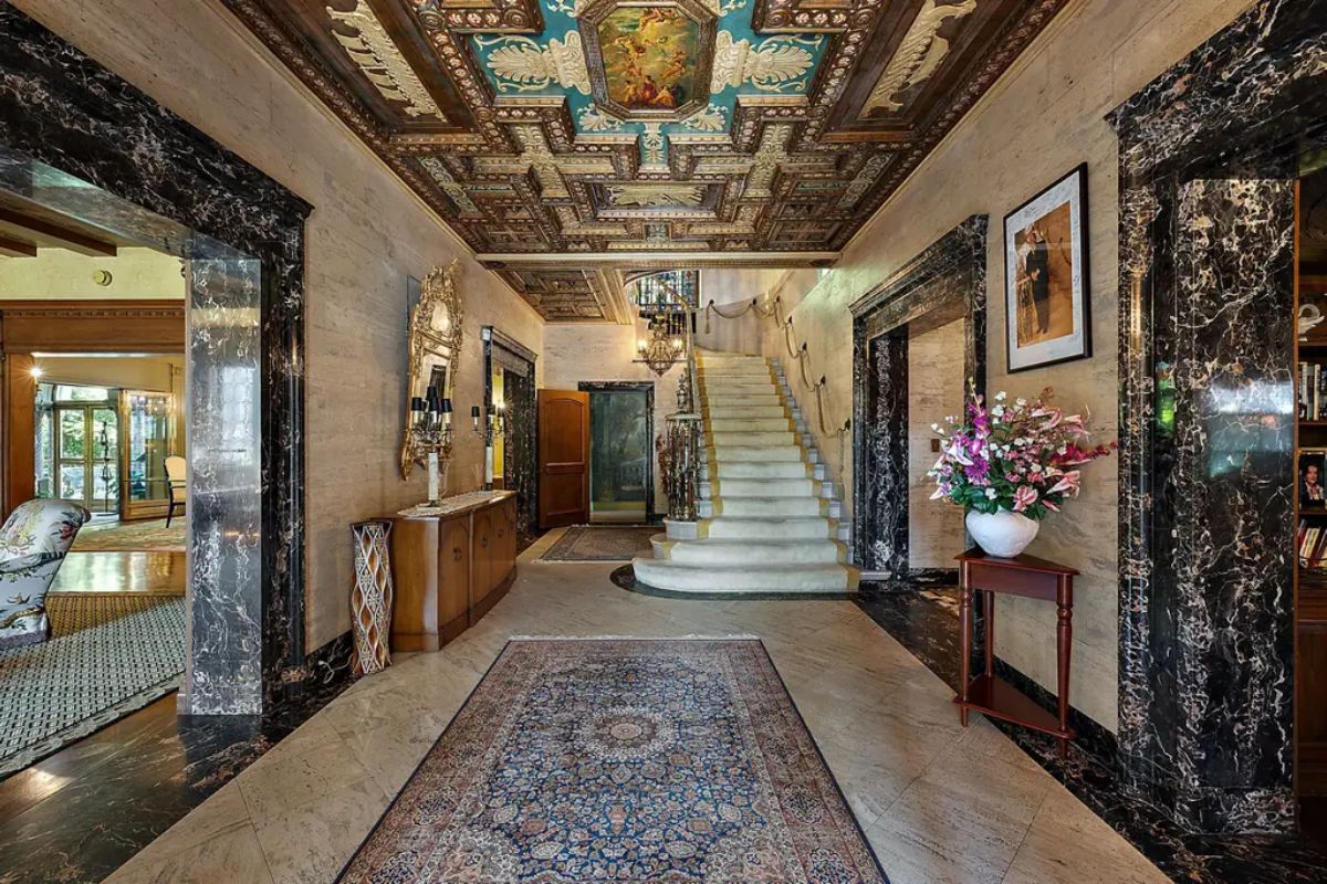A grand foyer showcases an intricately designed coffered ceiling with vibrant colors and detailed artwork.
