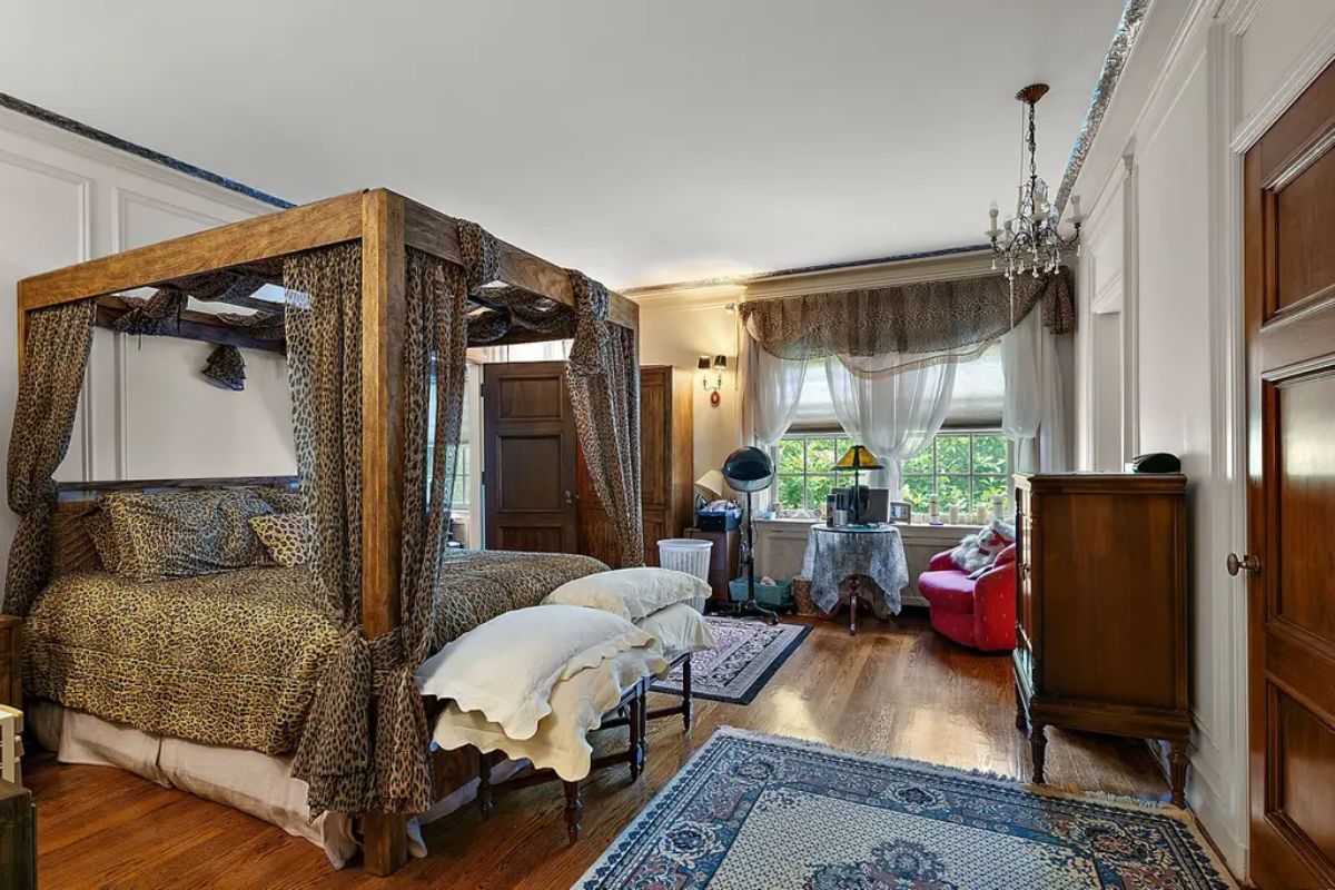 A large bedroom with a striking four-poster canopy bed with patterned drapery and matching bedding.