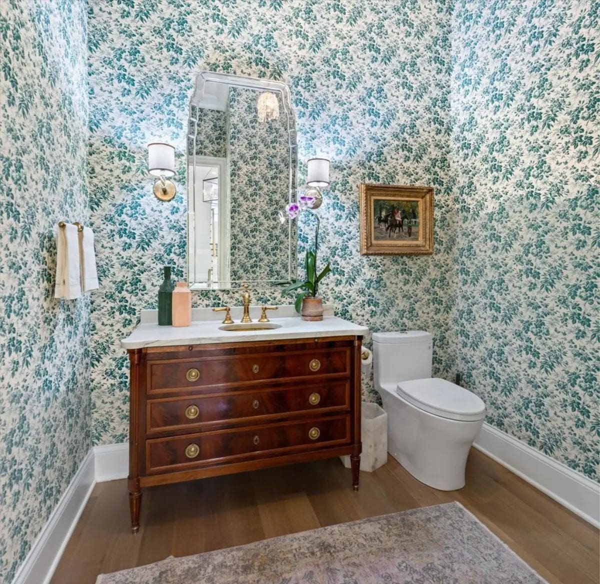 Powder room adorned with vintage-style floral wallpaper in green and white tones.