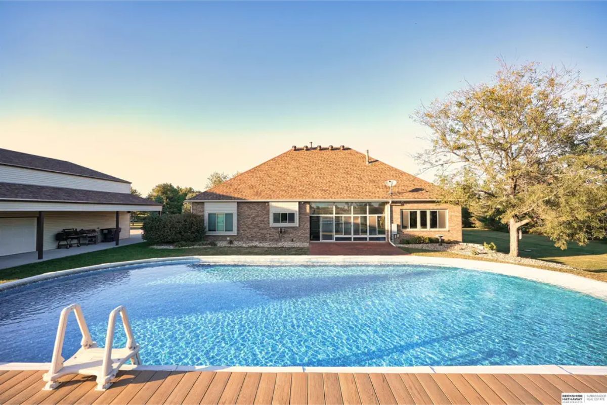 Expansive backyard featuring a large oval swimming pool with a surrounding deck.