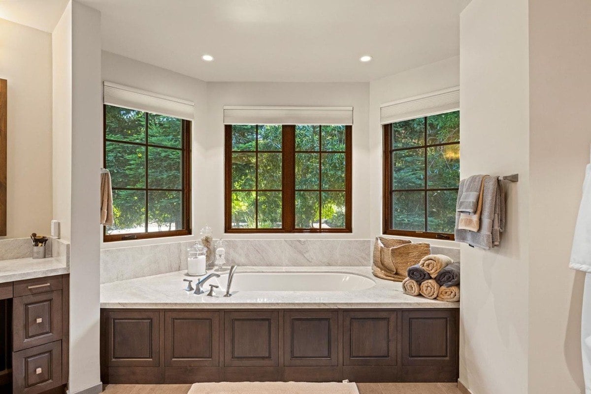 Poolside patio framed with lush greenery and a pristine in-ground swimming pool reflecting the evening sky.