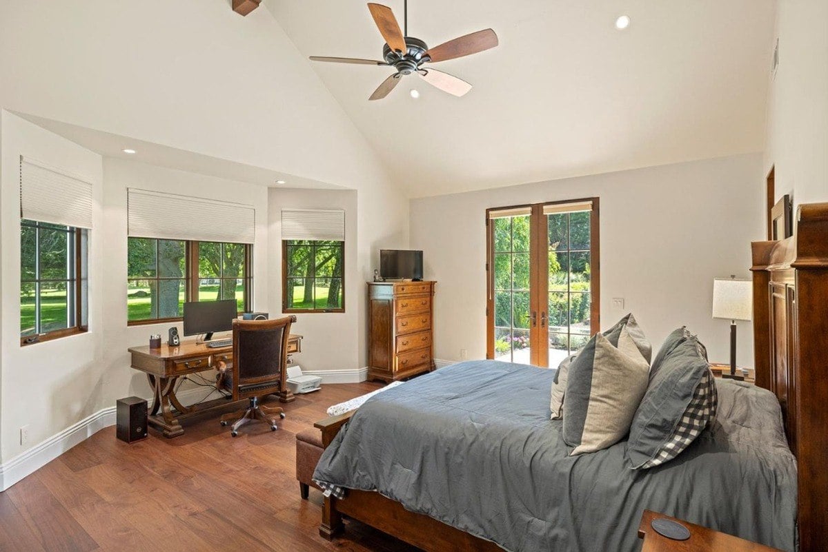 Family room centered around a stone fireplace with a mounted painting and custom wood cabinetry.