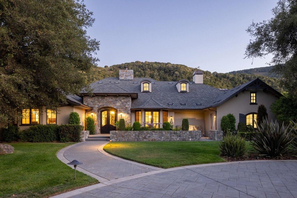 Grand entrance with stonework, an arched doorway, and a manicured pathway leading to the front door.