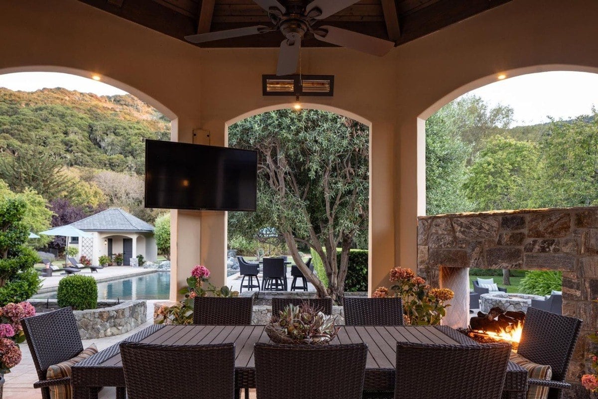 Dining area under vaulted arches overlooks the pool and garden through large openings.