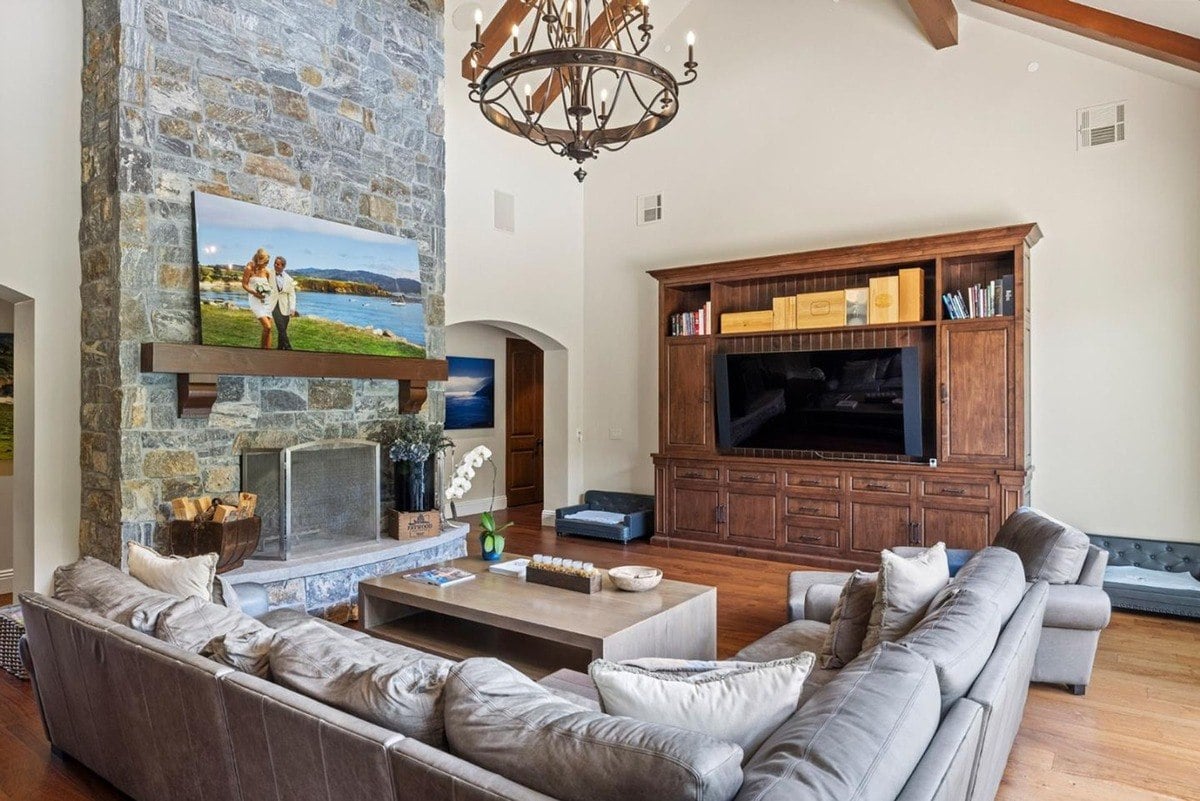 Cozy seating area centered around a stone fireplace, paired with a large wooden media cabinet for entertainment.