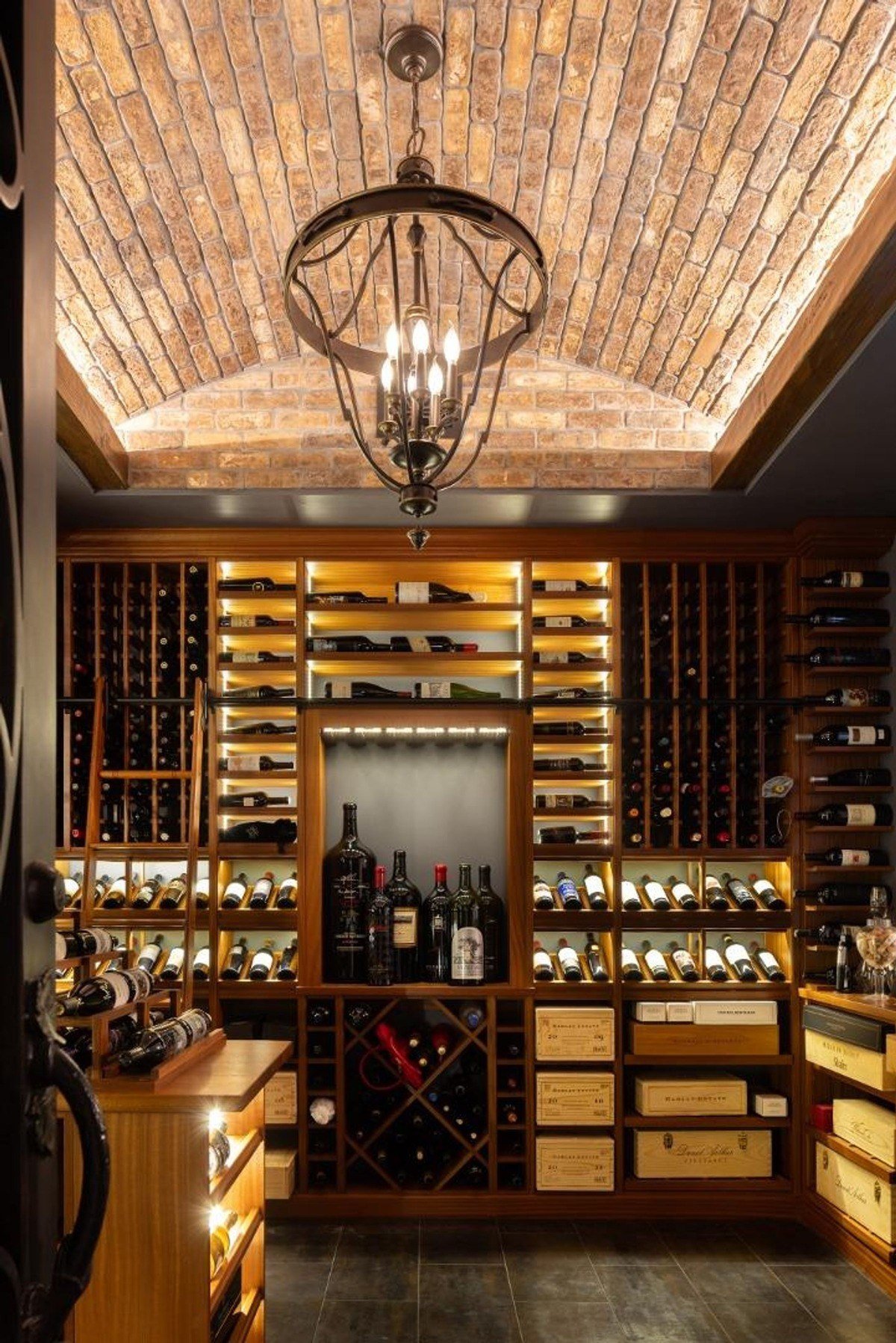 Wine cellar featuring a brick-arched ceiling, ambient lighting, and organized wooden shelving.