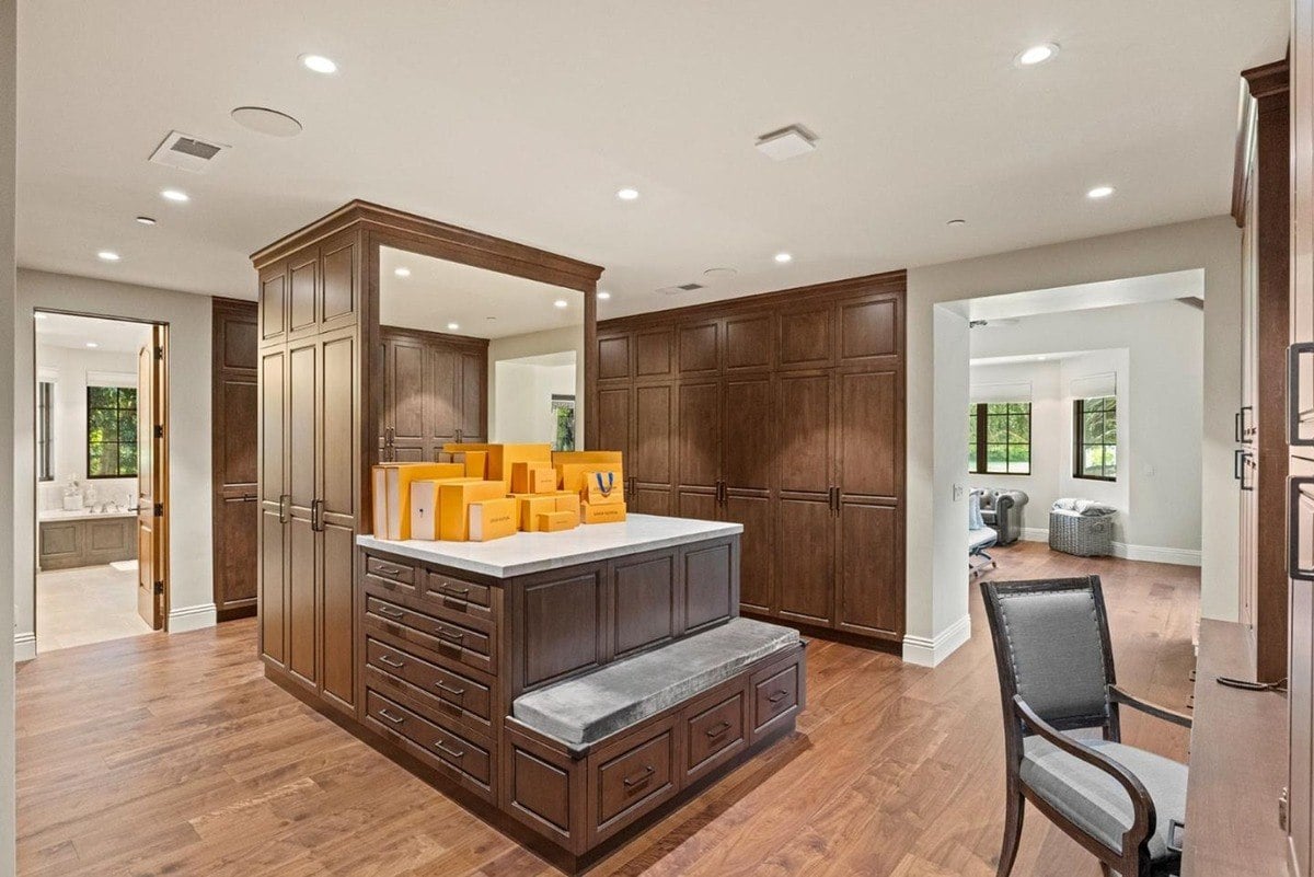 Walk-in closet with a central storage island, full-height cabinetry, and a makeup vanity area.