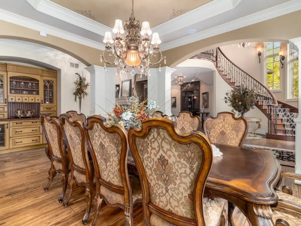 The formal dining room showcases intricate wood chairs arranged around an elegant table.