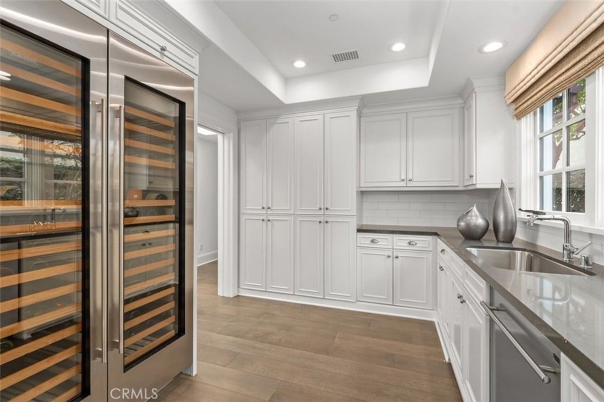 Pantry area with custom cabinetry, a large wine fridge, and a stainless steel sink.