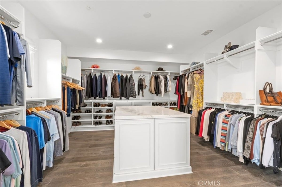 Walk-in closet with custom shelving, hanging racks, and an island centerpiece for added storage.
