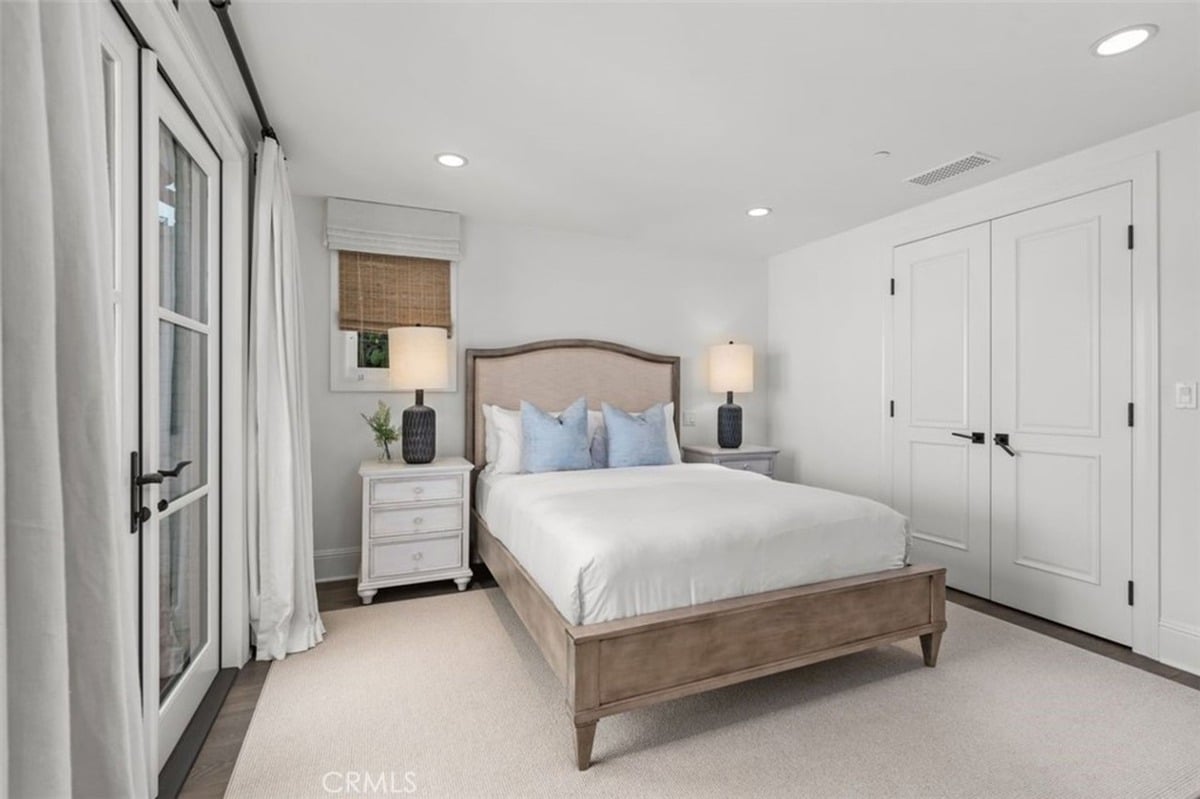 Elegant bedroom featuring a cushioned bed, matching nightstands, and access to an outdoor patio.