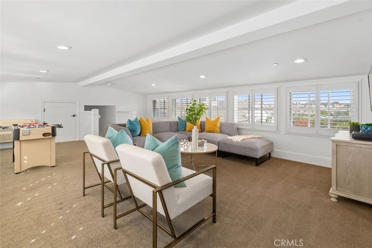 Bright entertainment room with a sectional sofa, foosball table, and multiple seating options.