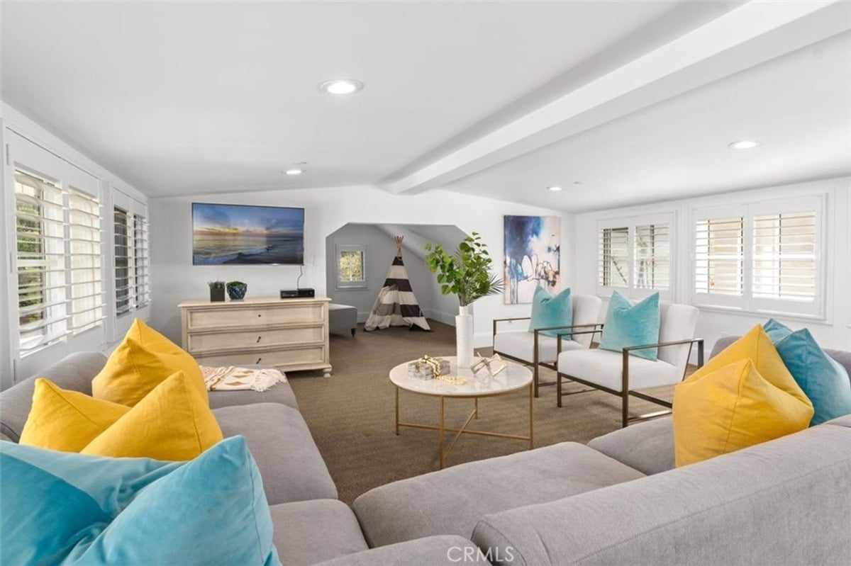 Relaxed living space showcasing colorful cushions, a flat-screen TV, and a tent-shaped corner area.