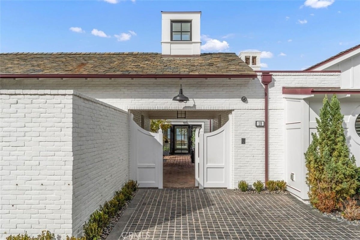 Welcoming gated entrance leads to a charming white brick exterior.