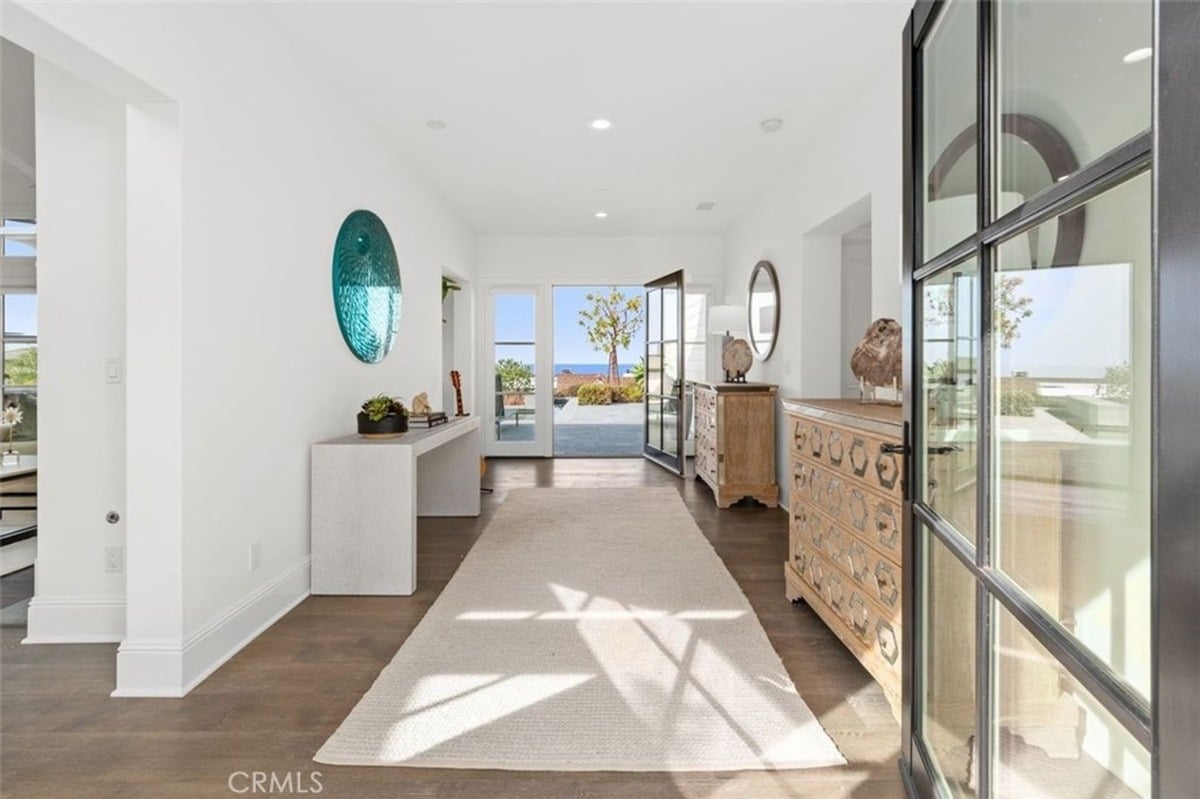 Elegant entryway with a long rug and stylish decor leads to the outdoor patio.