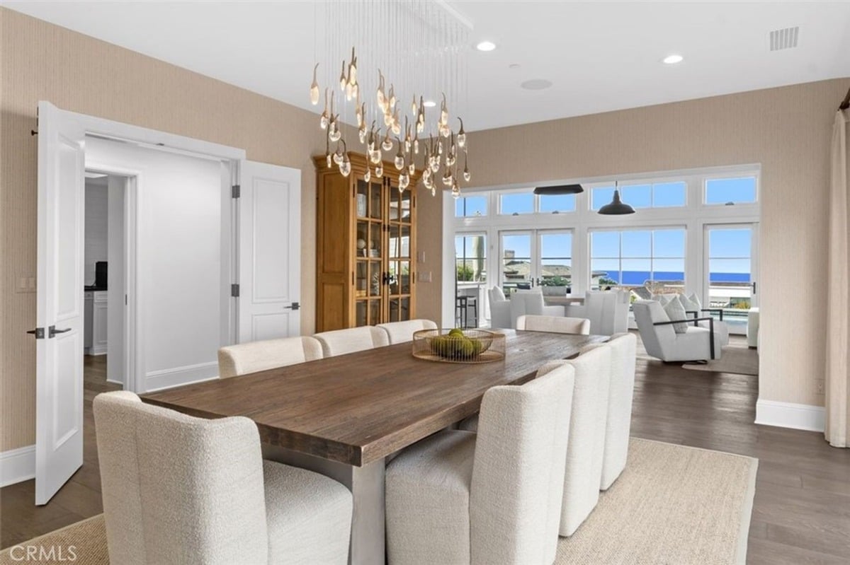 Modern dining room features a wooden table under a striking chandelier.