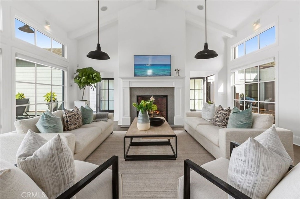 Spacious living room with white sofas centers around a sleek fireplace.