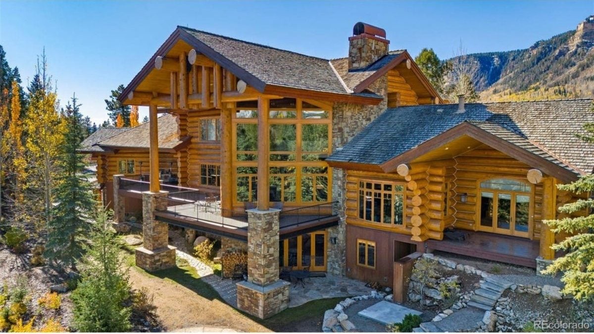 Exterior showcases tall vertical beams supporting the covered deck and an array of wide windows offering panoramic views.