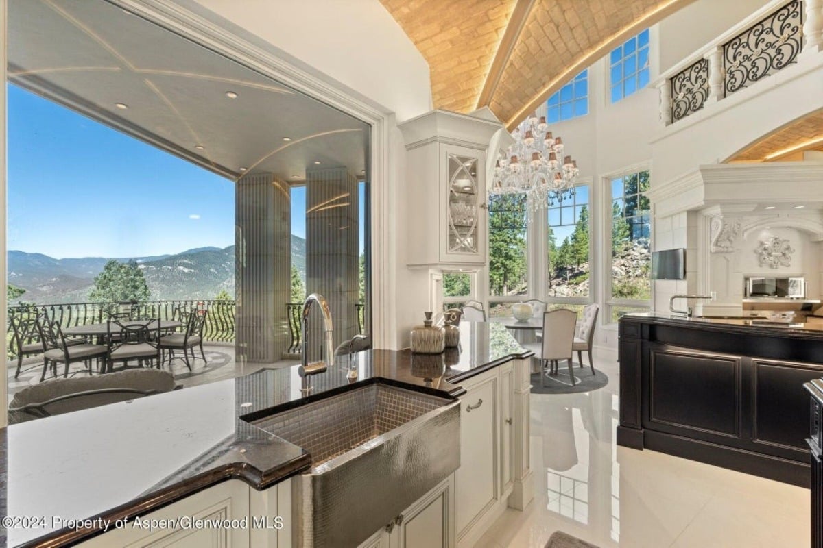 Sliding glass doors open to a sheltered outdoor dining area framed by stone columns.
