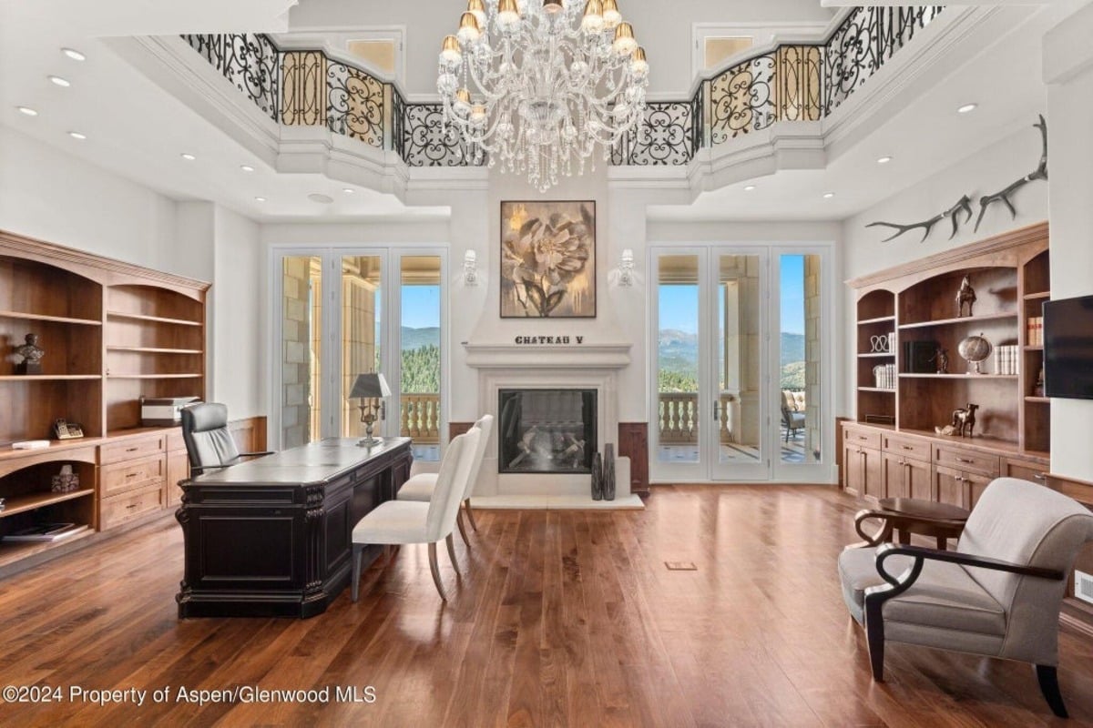 Stately bookshelves line the walls of the office, framing a central workspace with a rich wood executive desk.