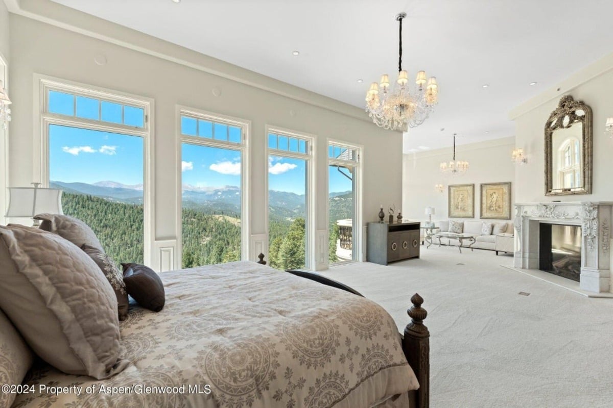Panoramic windows offer uninterrupted views of lush greenery and mountain peaks, filling the room with natural beauty.