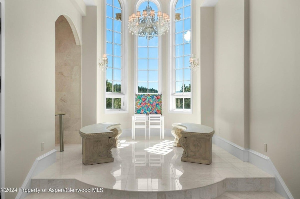 Sculpted stone benches face a grand arched window that fills the space with light and offers serene views.