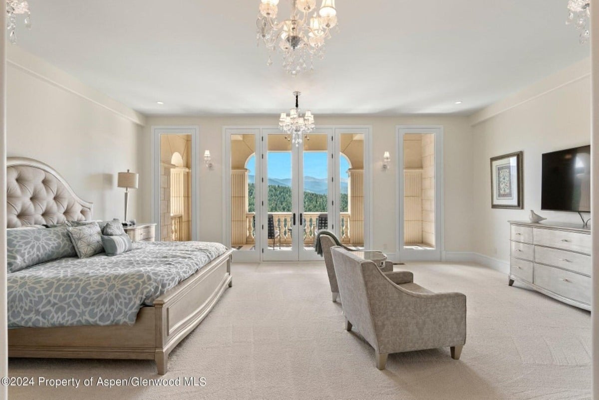 Plush armchairs and a tufted bed frame provide comfort in the serene guest suite.