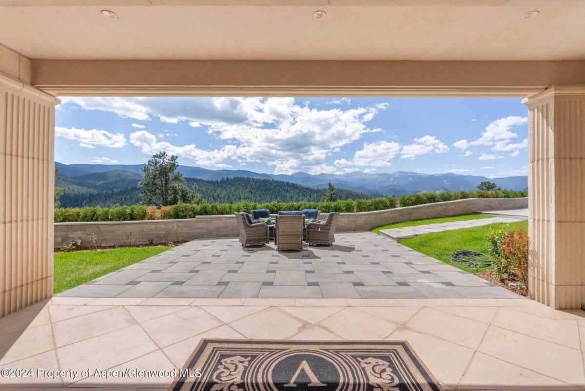 Paved patio holds a stylish lounge set positioned for unobstructed views of greenery and distant mountains.