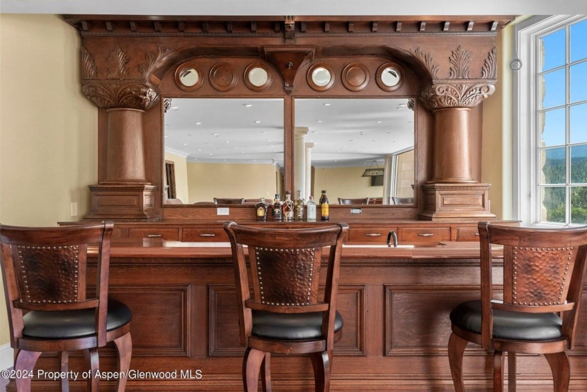 Built-in bar features intricate wood carvings and pillars that create a striking focal point in the entertainment space.
