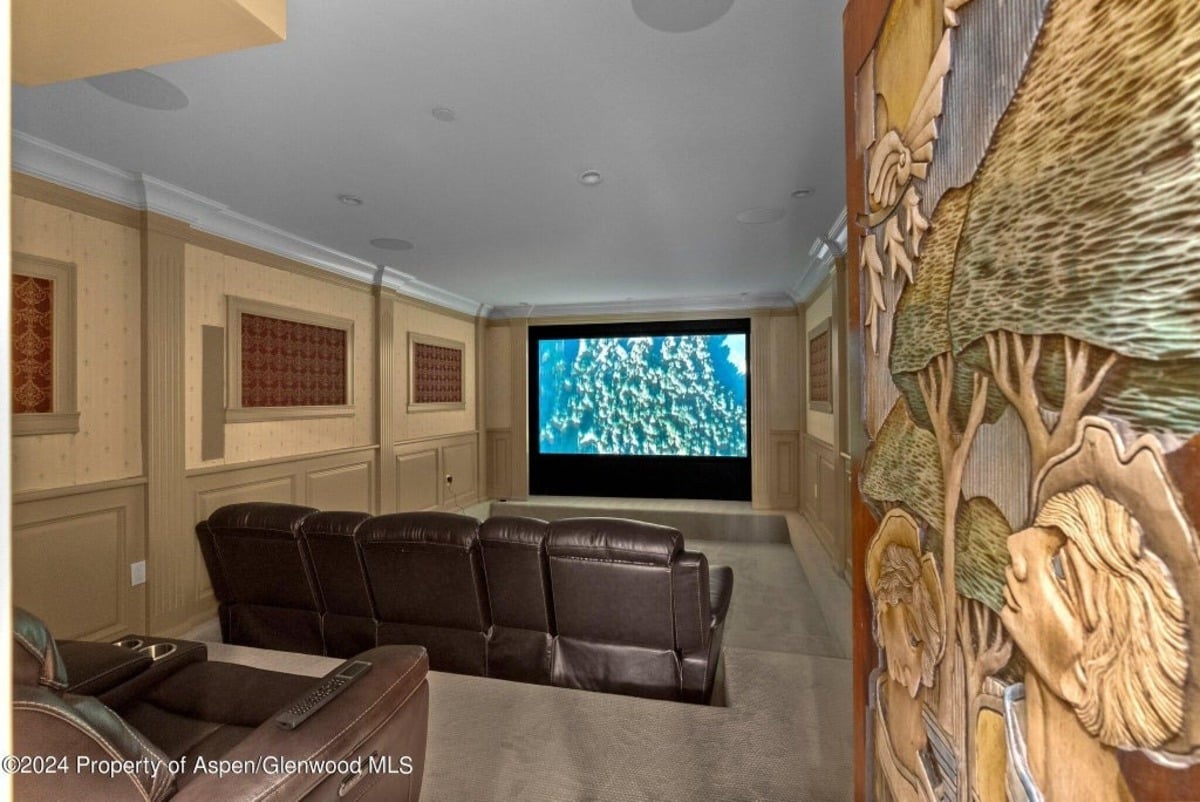 Plush leather recliners are arranged in rows facing a large projector screen for a true cinema experience.