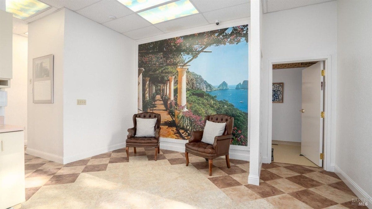 Lounge area with two leather chairs, scenic mural artwork, and soft overhead lighting.