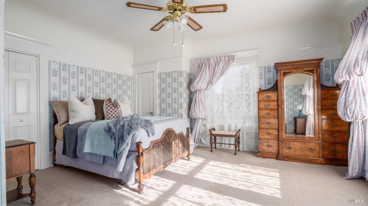 Bedroom presents a vintage bed frame, floral wallpaper, and lace-trimmed curtains with a matching canopy.