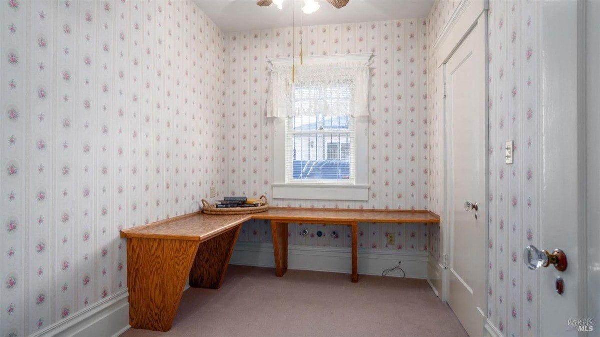 Small room features floral wallpaper, a built-in corner desk, and a lace-trimmed window.