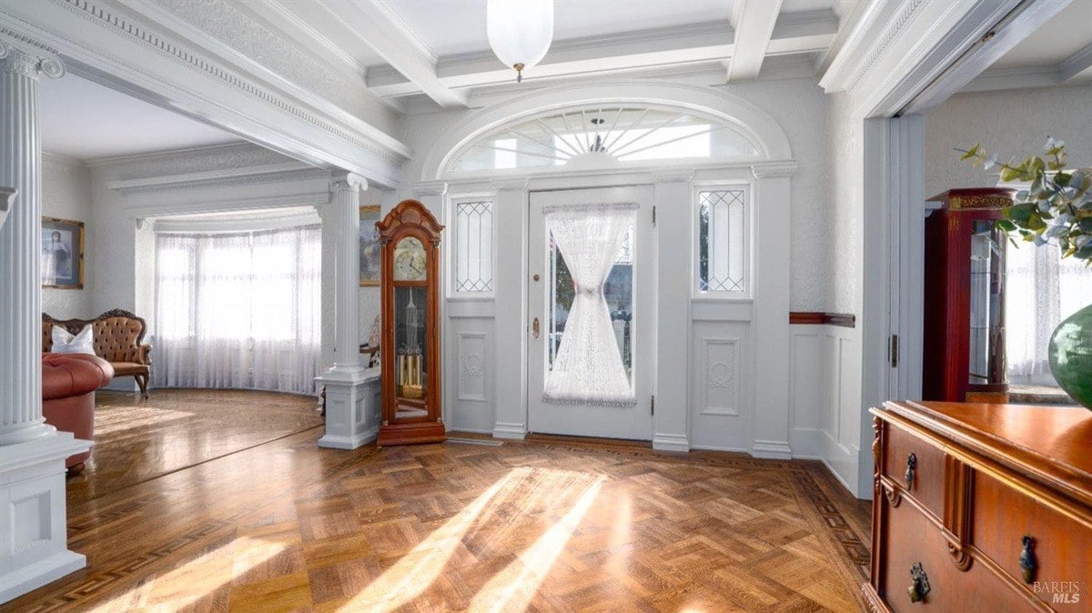 Entryway showcases intricate woodwork, a coffered ceiling, and stained glass details surrounding the front door.
