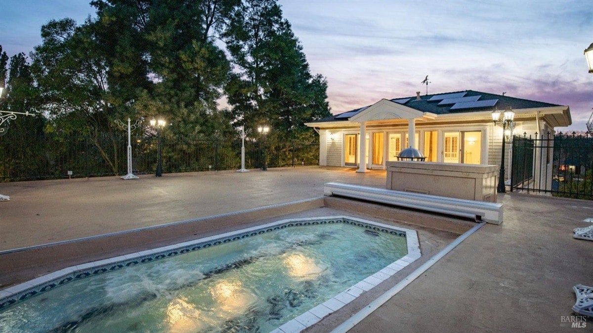 Outdoor spa and pool area is accented by surrounding lights and a cozy pool house.