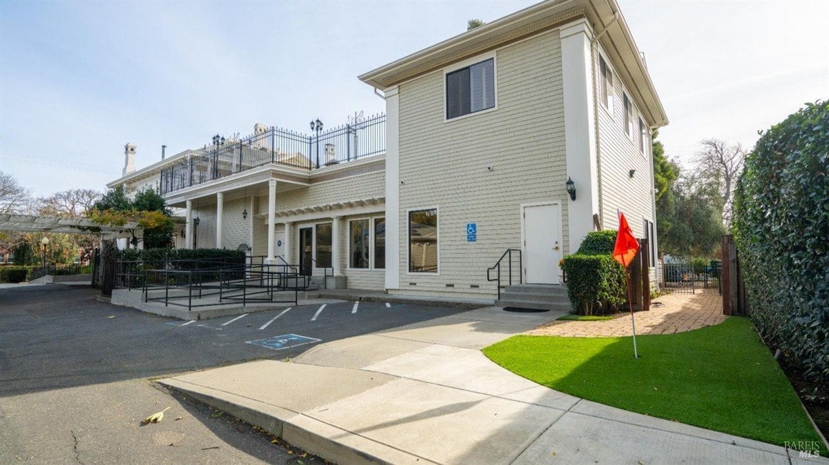 Side view showcases a modern building extension with accessibility features, including a ramp and designated parking.