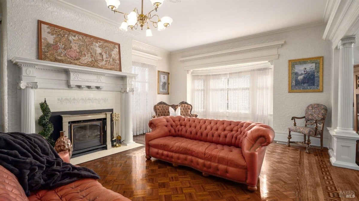 Living room presents tufted orange sofas, an ornate fireplace with decorative molding, and a large bay window with lace curtains.