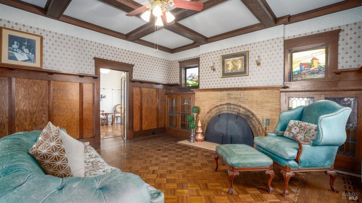 Living room has hardwood floors, wood paneling, a fireplace, and a teal upholstered chair.
