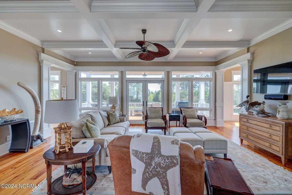 Living room has hardwood floors, coffered ceiling, and seating area.