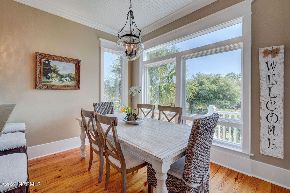 Dining area has hardwood floors, whitewashed table, and window view.