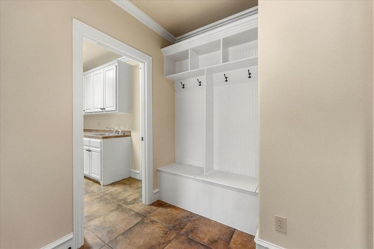 Mudroom area with white cubby shelves, bench seating, and adjacent entry to the laundry room.
