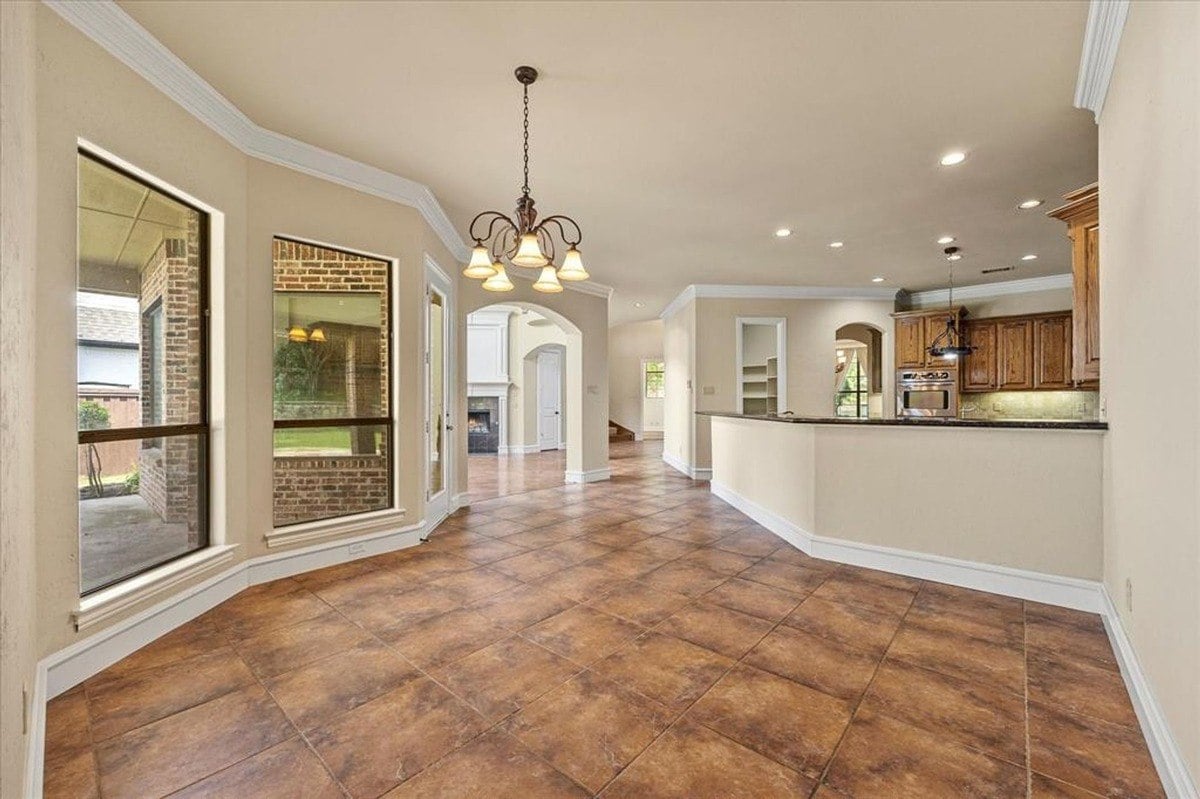 Breakfast nook with tiled flooring, arched entranceways, and large windows overlooking the backyard.