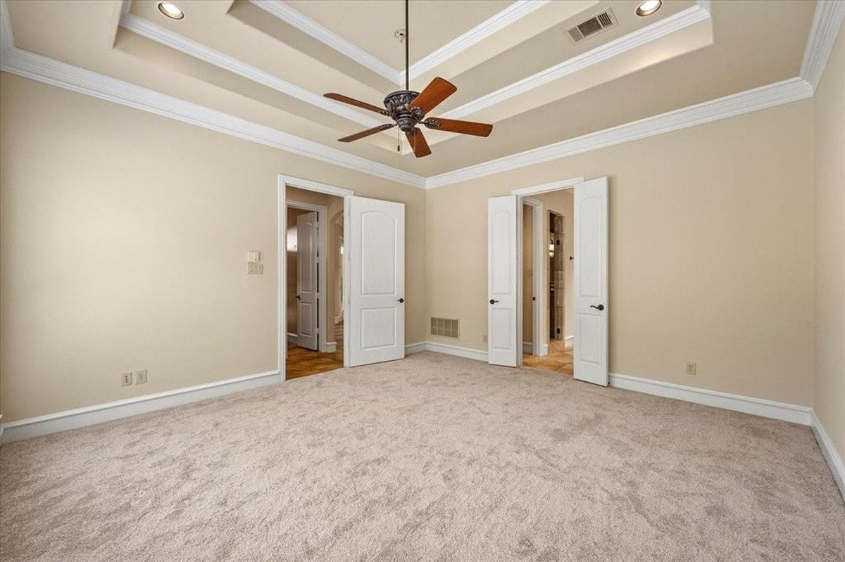 Alternate view of the primary bedroom showing dual-door access to the en suite bathroom and connecting hallway.