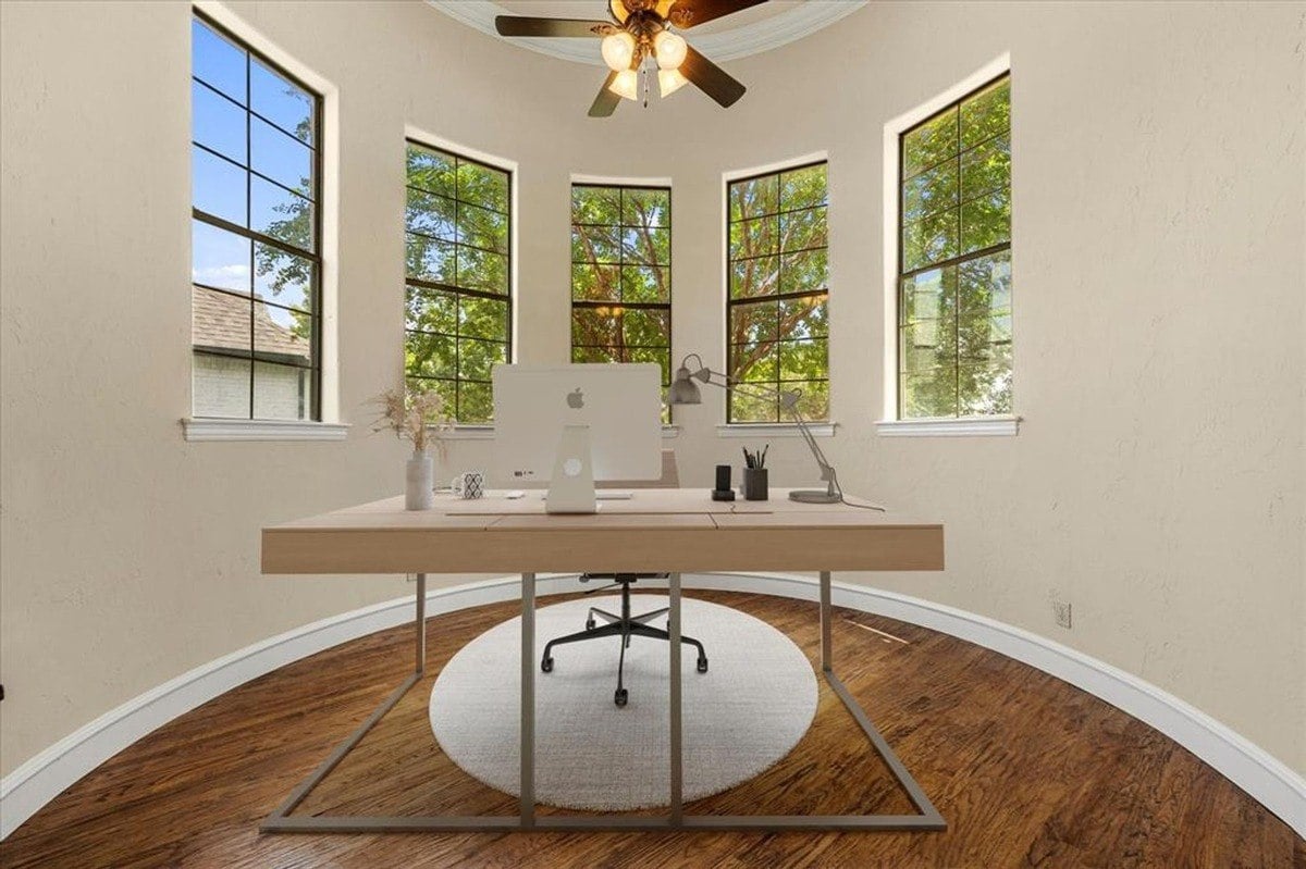 Dining area with hardwood floors, crown molding, and a central chandelier next to a large window.