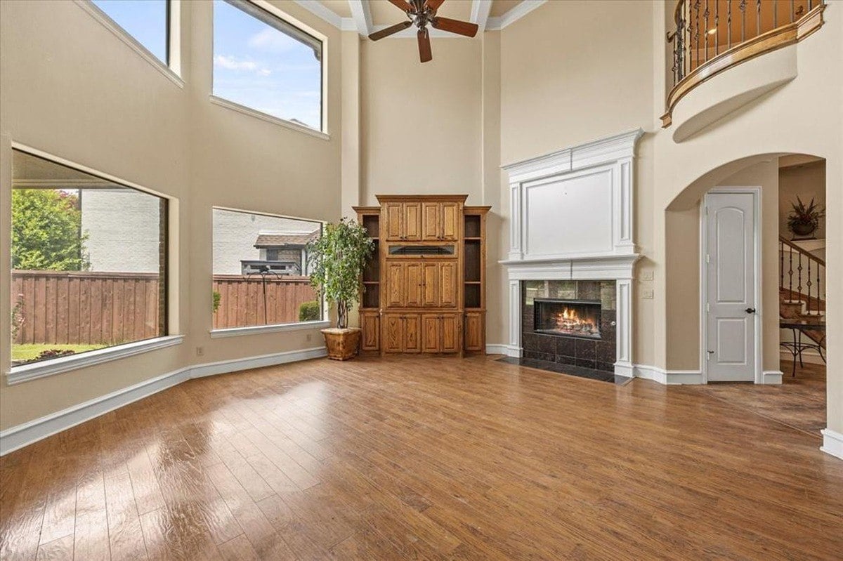 Living room with high ceilings, a fireplace, built-in cabinetry, and expansive windows overlooking the backyard.