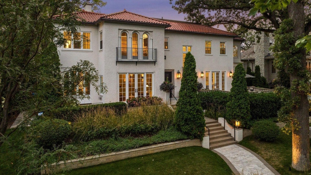 Large white house with a red tile roof, landscaping, and a stone walkway.
